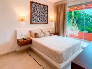 a bedroom with a large bed and a large window at Mabay in Zihuatanejo
