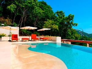 a swimming pool with red chairs and umbrellas at Mabay in Zihuatanejo