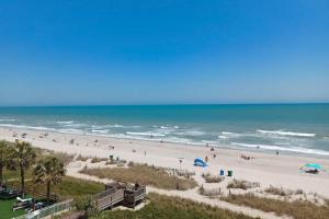a group of people on a beach with the ocean at Blue Palmetto Vacation Rentals in Myrtle Beach +2 photos