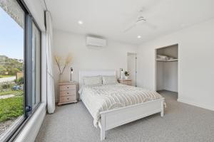 a white bedroom with a bed and a window at Inverloch Seaside Escape in Inverloch