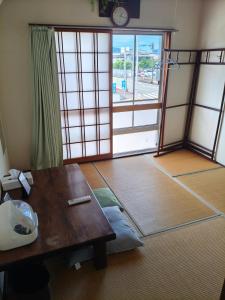 a living room with a table and a large door at Guest House Aki in Nichinan