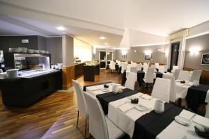 a dining room with white tables and white chairs at Hotel San Rocco in Muggia