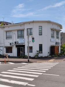 a white building on the corner of a street at Guest House Aki in Nichinan