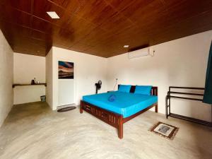 a bedroom with a blue bed with a wooden ceiling at Kora Beach House & Restaurant Cafe in Ampara