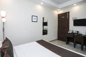 a bedroom with a bed and a desk and a television at Hotel O The Signature inn in Indirapuram