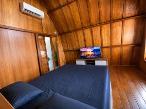 a bedroom with a bed and a tv in it at Wavez Bungalow in Selong Belanak