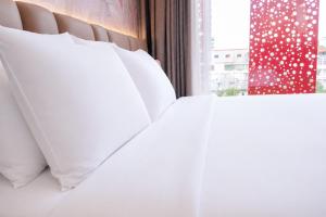 a white bed with white pillows and a window at Y Hotel Phan Đình Phùng in Can Tho