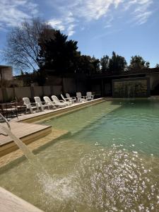 a swimming pool with chairs and a fountain at Ranqueles in Villa Carlos Paz