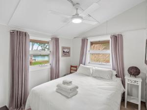 a bedroom with a white bed with towels on it at River Cottage in Mylestom