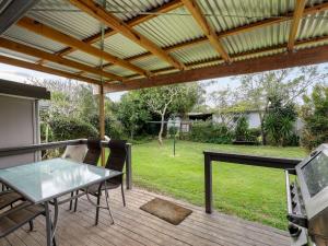 a patio with a table and chairs on a deck at River Cottage in Mylestom