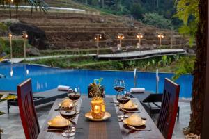 a wooden table with wine glasses and a table with a pool at Pu Luong EcoLuxe Resort & Spa in Pu Luong +6 photos