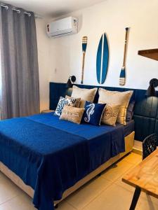 a bedroom with a blue bed with pillows on it at Apartamento Centro Bertioga Casal e Família - Ar Condicionado - Praia da Enseada in Bertioga