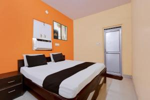 a bedroom with a large bed with an orange wall at Hotel O Royal Inn Hotel in Hāpur