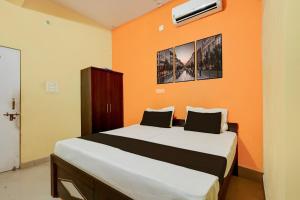 a bedroom with a large bed with an orange wall at Hotel O Royal Inn Hotel in Hāpur