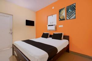 a bedroom with a bed with an orange wall at Hotel O Royal Inn Hotel in Hāpur