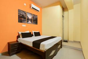 a bedroom with a bed with an orange wall at Hotel O Royal Inn Hotel in Hāpur +27 photos