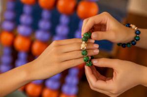 a woman is putting a bead on a persons hand at OUTRIGGER Phi Phi Island Resort in Phi Phi Islands