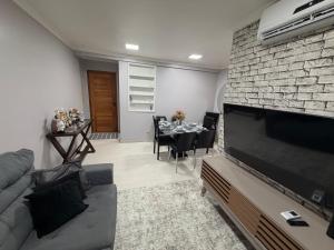 a living room with a television and a table with chairs at Garden aconchegante in Manaus