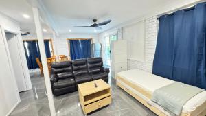 a bedroom with a bed and a black leather couch at Pool House with 3 BDR 2 AC in Marsden +18 photos