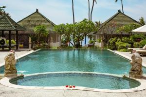 a swimming pool with two statues in front of a house at Poinciana Resort in Tejakula