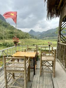 a table and two chairs on a deck with a flag at Homestay mây phía đồi in Lũng Tiềm
