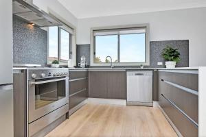 a large kitchen with stainless steel appliances and wooden floors at Finns at Caves Beach Resort in Caves Beach