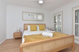 a bedroom with a large bed and two windows at Finns at Caves Beach Resort in Caves Beach