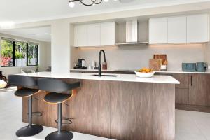 a kitchen with white cabinets and a counter with stools at Mount View Escape at Millfield in Millfield +18 photos