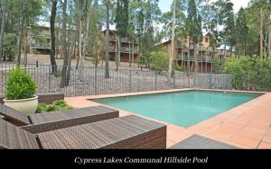 a swimming pool with two chairs and a fence at Villa 1br Merlot Villa located within Cypress Lakes Resort in Pokolbin