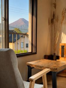 a table and a chair in a room with a window at Three Maples Fujiyoshida in Fujiyoshida