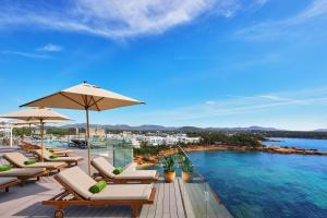 a pool with chairs and umbrellas on a balcony at Meliá Ibiza - Adults Only in Santa Eularia des Riu