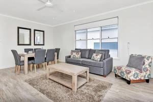 a living room with a couch and a table and chairs at Beach Escape at Caves Beach Villas in Caves Beach