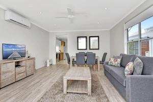 a living room with a gray couch and a table at Beach Escape at Caves Beach Villas in Caves Beach