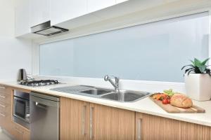 a kitchen with a sink and fruits and vegetables on a counter at Beach Escape at Caves Beach Villas in Caves Beach +31 photos