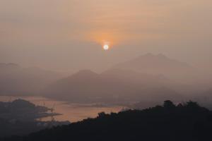 a sun setting over a body of water with mountains at 纏matoi in Maizuru