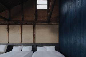 two beds in a room with a blue wall at 纏matoi in Maizuru