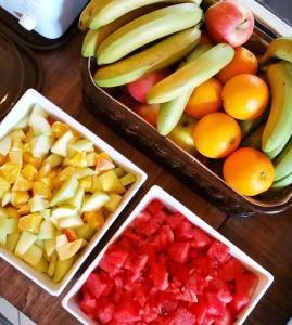 a table topped with bowls of fruit including apples oranges and bananas at Inhawi Boutique Hostel in St. Julianʼs