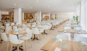 a dining room with tables and white chairs at SOL by Meliá Palmanova Mallorca in Palmanova