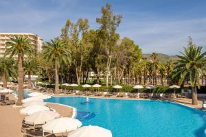 a swimming pool with white umbrellas and palm trees at SOL by Meliá Palmanova Mallorca in Palmanova +48 photos