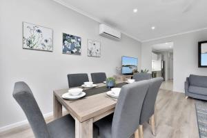 a dining room with a wooden table and chairs at Ocean Mist at Caves Beach Villas in Caves Beach +38 photos