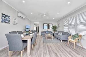 a dining room and living room with a table and chairs at Ocean Mist at Caves Beach Villas in Caves Beach