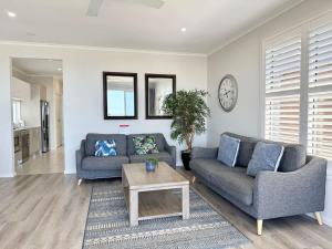 a living room with two couches and a table at Ocean Mist at Caves Beach Villas in Caves Beach