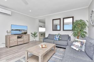 a living room with a couch and a tv at Ocean Mist at Caves Beach Villas in Caves Beach