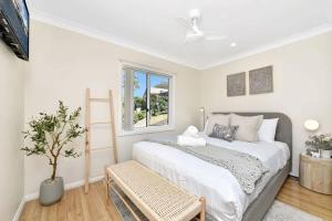 a white bedroom with a bed and a window at Upper Deck On Dobell in Wangi Wangi