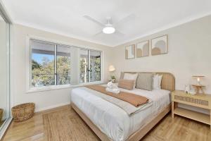 a white bedroom with a large bed and a window at Upper Deck On Dobell in Wangi Wangi