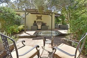 a patio with a table and chairs and a fireplace at Olive Grove 1 Studio in Pokolbin +4 photos