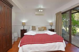 a bedroom with a bed with a red and white blanket at Olive Grove 1 Studio in Pokolbin