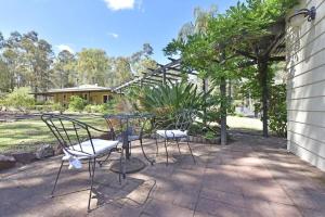 two chairs and a table on a patio at Olive Grove 1 Studio in Pokolbin