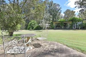a patio with a table and chairs in a yard at Olive Grove 1 Studio in Pokolbin