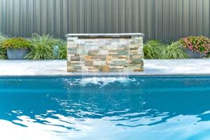a swimming pool with a stone wall and a water fountain at Sea Sand and Serenity at Stockton - Stunning Sophistication in Stockton
